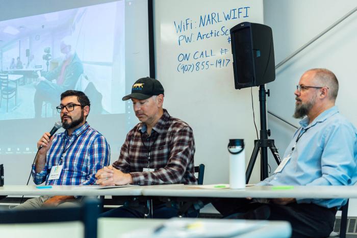 Figure 1. During a morning panel on Day 1 in Utqiaġvik, North Slope participants described the challenges they face from permafrost thaw and coastal erosion. From left, Griffin Hagle-Forster, Executive Director of TNHA, Yves Brower, Assistant Superintendent of BUECI, and Scott Evans, Director of the North Slope Borough Port Authority, discussed challenges related to permafrost foundation, utility infrastructure, and coastal erosion and sea walls, respectively. Photo courtesy of Lloyd Pikok/UIC Science. Figure 1. During a morning panel on Day 1 in Utqiaġvik, North Slope participants described the challenges they face from permafrost thaw and coastal erosion. From left, Griffin Hagle-Forster, Executive Director of TNHA, Yves Brower, Assistant Superintendent of BUECI, and Scott Evans, Director of the North Slope Borough Port Authority, discussed challenges related to permafrost foundation, utility infrastructure, and coastal erosion and sea walls, respectively. Photo courtesy of Lloyd Pikok/UIC Science.