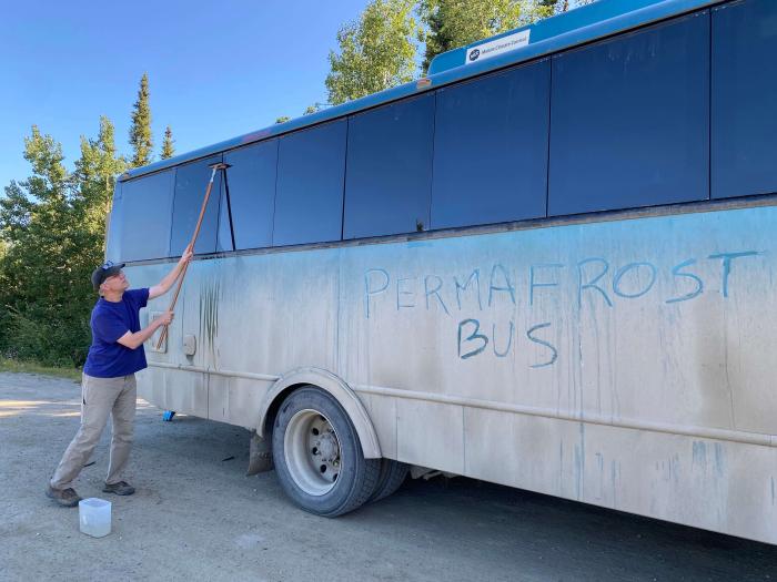 Figure 8. Transportation for the second half of the Symposium was provided by Fairbanks-based Northern Alaska Tour Company. NATC guide, John Peirce, washes the windows of the 24-passenger coach that provided facilities for a rolling workshop in the Prudhoe Bay Oilfield and along the Dalton Highway. Battelle ARO managed logistics for the Symposium. Photo courtesy of Jana Peirce. Figure 8. Transportation for the second half of the Symposium was provided by Fairbanks-based Northern Alaska Tour Company. NATC guide, John Peirce, washes the windows of the 24-passenger coach that provided facilities for a rolling workshop in the Prudhoe Bay Oilfield and along the Dalton Highway. Battelle ARO managed logistics for the Symposium. Photo courtesy of Jana Peirce.
